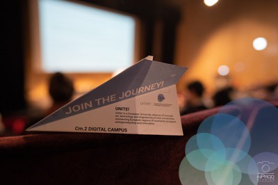 Image of a paper plane with a text that reads: "JOIN THE JOURNEY! Unite! is an European University alliance of innovation, technology and engineering of nine universities connecting European regions of economic prospect, entrepreneurship and innovation. Cm2 Digital Campus"
