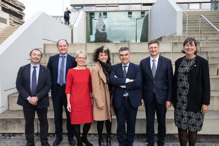 Photograph of a group of people standing in front of the TU Darmstadt university