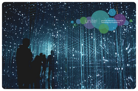 An image of an exhibition where you can see many lights hanging from the sky in a dark room and the silhouettes of people, reminding you of a network or space.