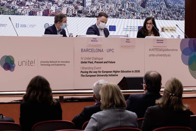 Three persons sitting at a desk during session at the event
