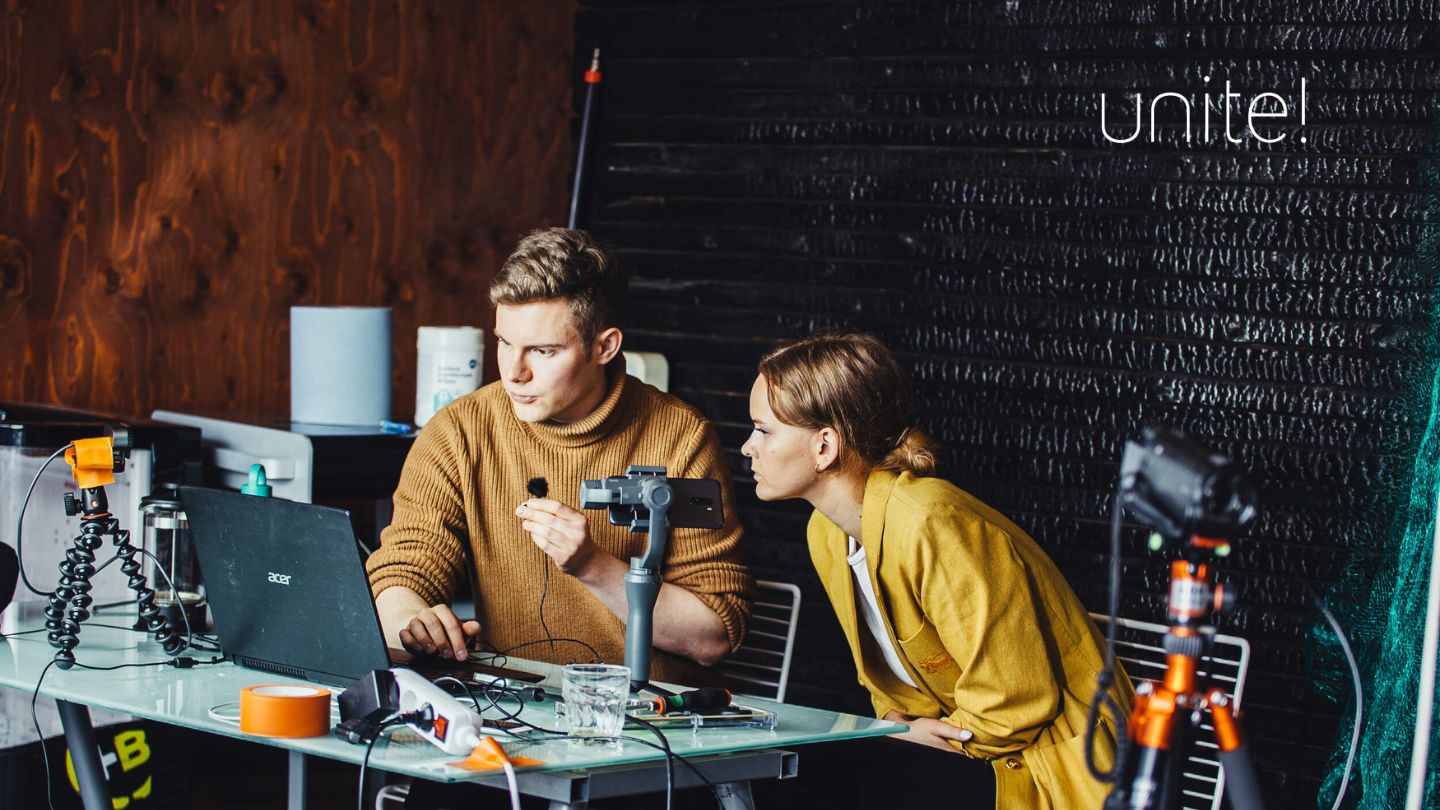 See larger image Two people setting up camera, microphones, laptops, and other equipment for an online training session