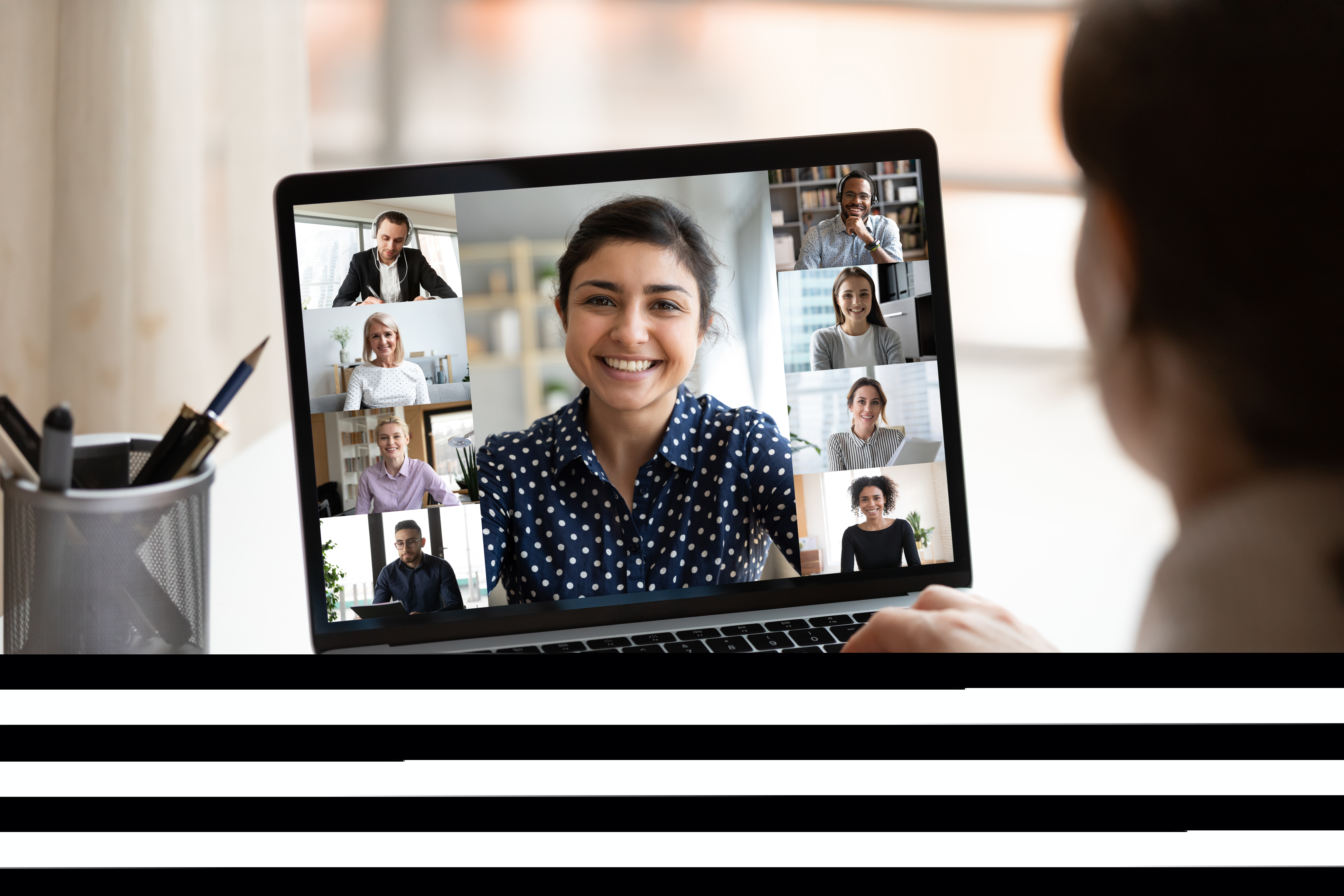 A person looking at a laptop screen full of people in a virtual meeting.