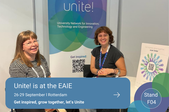 Two women sitting at the Unite! booth with a text that reads "Unite! is at the EAIE / 26-29 September l Rotterdam/ Get inspired, grow together, let’s Unite / Stand  F04"