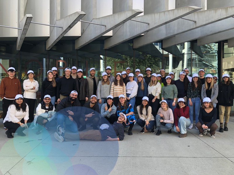 A big group of young students wearing the Unite! corporate cap in front of a university building.